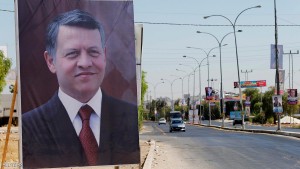 A poster of Jordan's King Abdullah is seen near electoral posters for parliamentary candidates ahead of the general elections on Tuesday, in Madaba city, near Amman